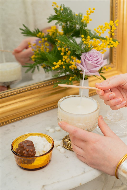 Geste de création d’une bougie avec un kit BOOGIE, dans une ambiance calme et naturelle propice à la détente.