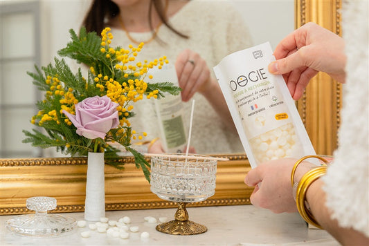 Personne créant une bougie parfumée dans un contenant en verre réutilisé.